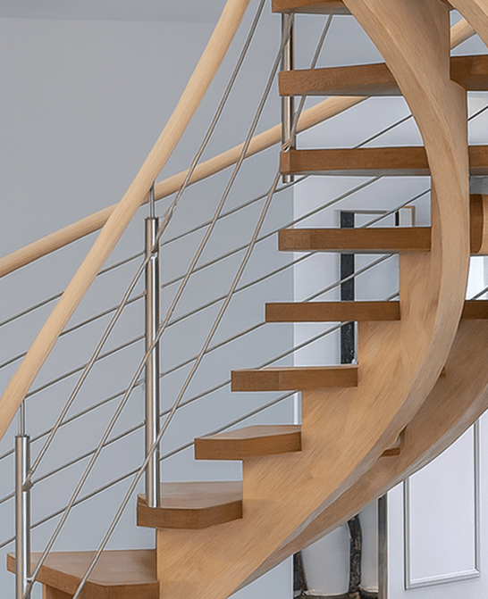 Escalier tournant moderne en bois clair avec garde-corps minimaliste à câbles métalliques et main courante assortie.