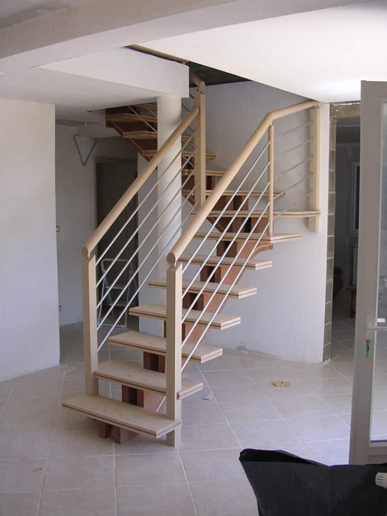 Escalier bois moderne, design intérieur en construction Escalier intérieur moderne en cours de construction, marches en bois clair et supports visibles, balustrade à câbles métalliques.